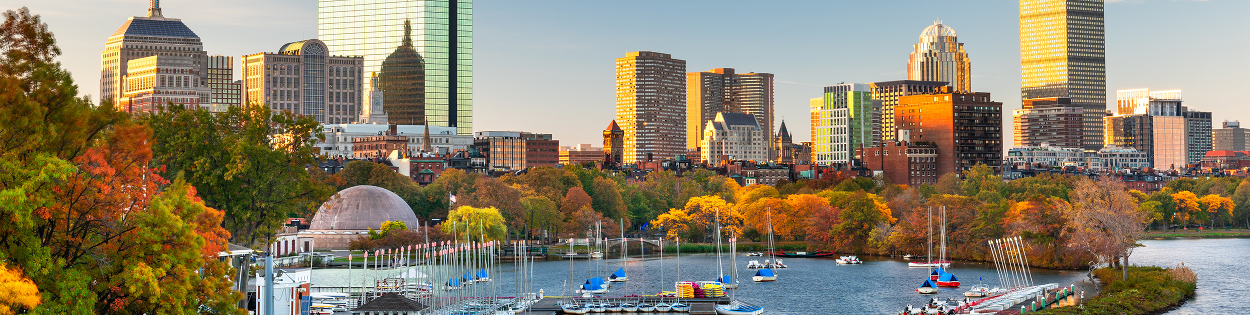 Boston Harbor in the Fall with boats in the water and beautiful color in the trees