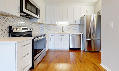 kitchen with white cabinets, stainless steel appliances and hardwood flooring