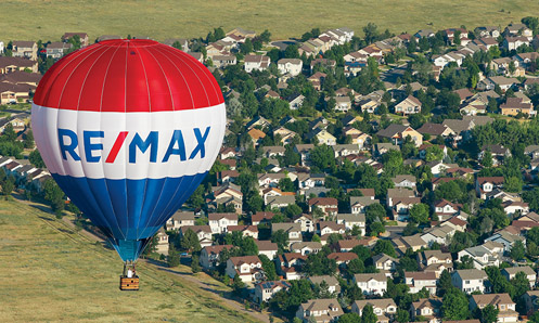 RE/MAX balloon flying over a neighborhood.