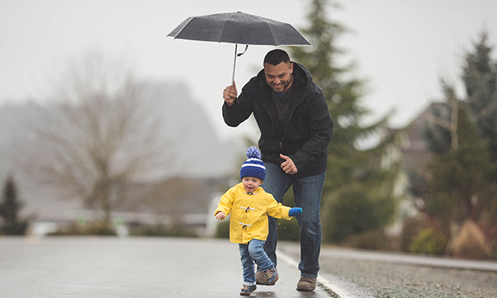 Happy man playing with happy child on a rainy day.