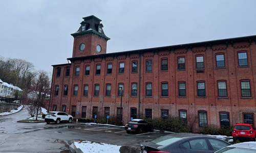 large brick building with lots of windows surrounded by a cloudy sky