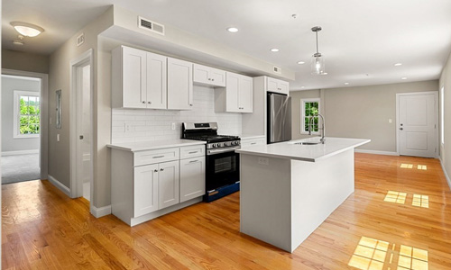 kitchen with white cabinets, stainless steel and black appliances and hardwood flooring