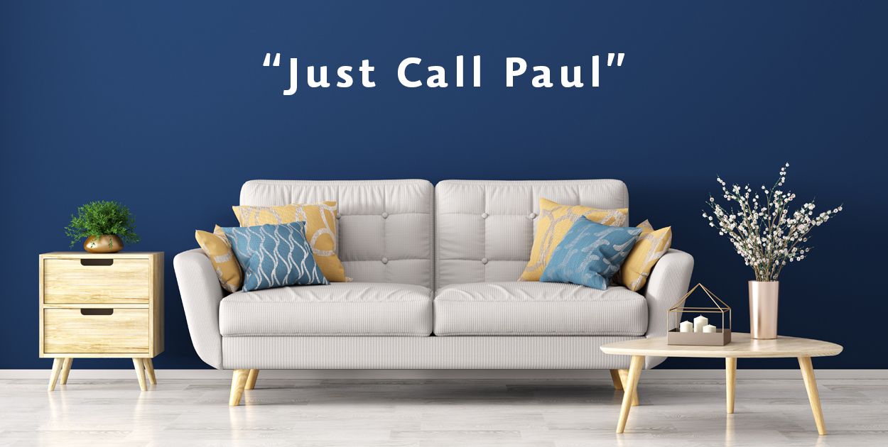 photo of couch with Just Call Paul written on a blue wall behind it