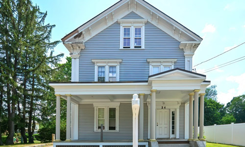 26 Church Street Westborough, MA 01587 Gray Victorian style home with white trim, covered entranceway with white door, stone steps and a white fence shown to the right