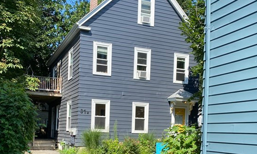 Exterior of multi family home - blue with white trim, peaked roof and double porches on the left side