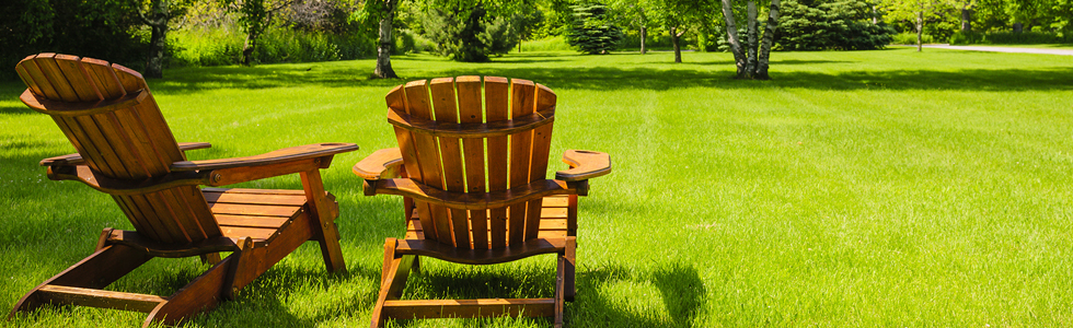 two wooden adirondack chairs sitting on green lawn