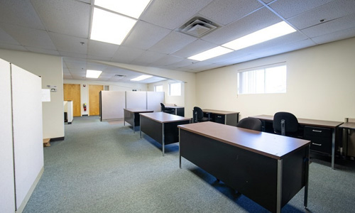 a commercial office space with several desks and chairs in the room