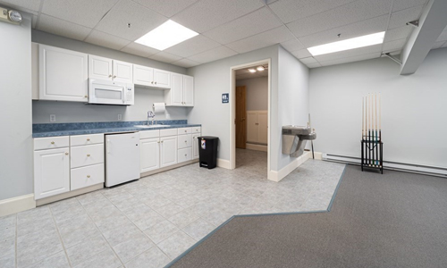 a commercial office space with a kitchenette area with plenty of white cabinets